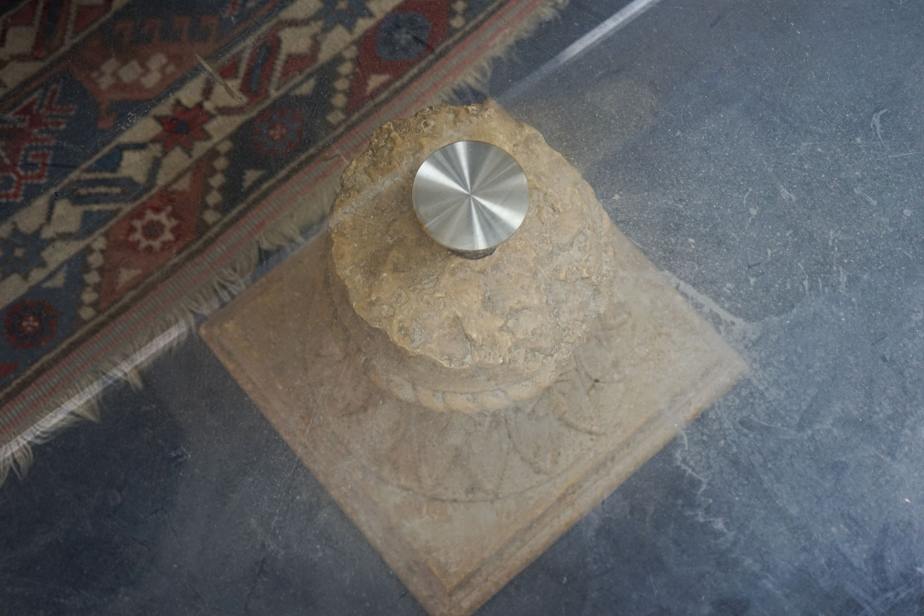 A contemporary oval glass top coffee table on simulated carved stone base, width 118cm, depth 79cm, height 41cm